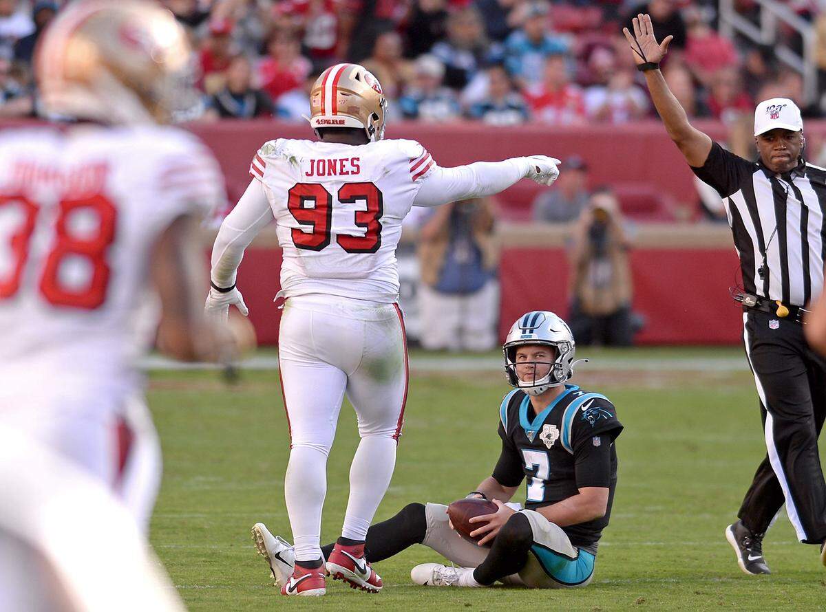 Carolina Panthers quarterback Kyle Allen, center, sits on the turf after being sacked by San Francisco 49ers defensive lineman D.J. Jones, left, during fourth quarter action at Levi’s Stadium in Santa Clara, CA on Sunday, October 27, 2019.The 49ers defeated the Panthers 51-13.
