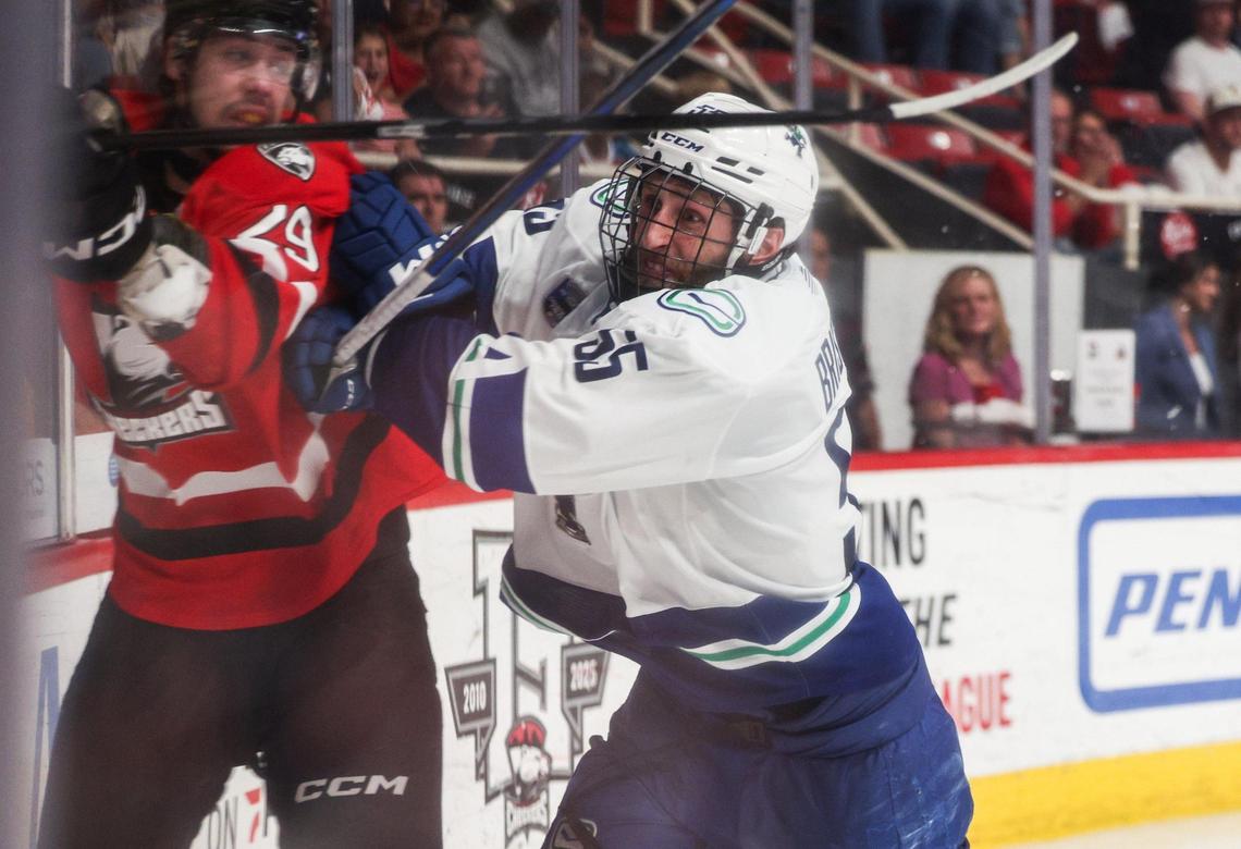 Checkers left winger John Leonard, left, gets shoved into the wall by Canucks defender Guillaume Brisebois during the Calder Cup opener at Bojangles Coliseum in Charlotte, NC on Friday, June 13, 2025. The Canucks won the first game, 4-3, after two overtime periods.