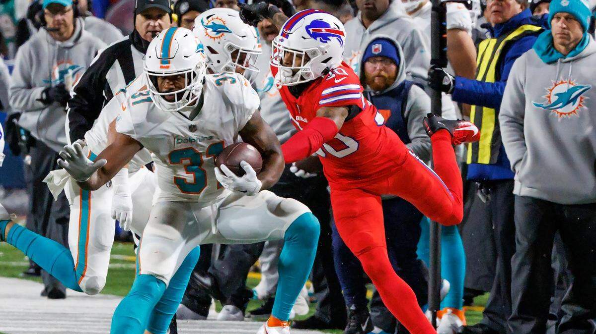 Miami Dolphins running back Raheem Mostert (31) runs the football against Buffalo Bills safety Damar Hamlin (3) and Bills cornerback Dane Jackson (30) during fourth quarter of an NFL football game at Highmark Stadium on Saturday, December 17, 2022 in Orchard Park, New York.