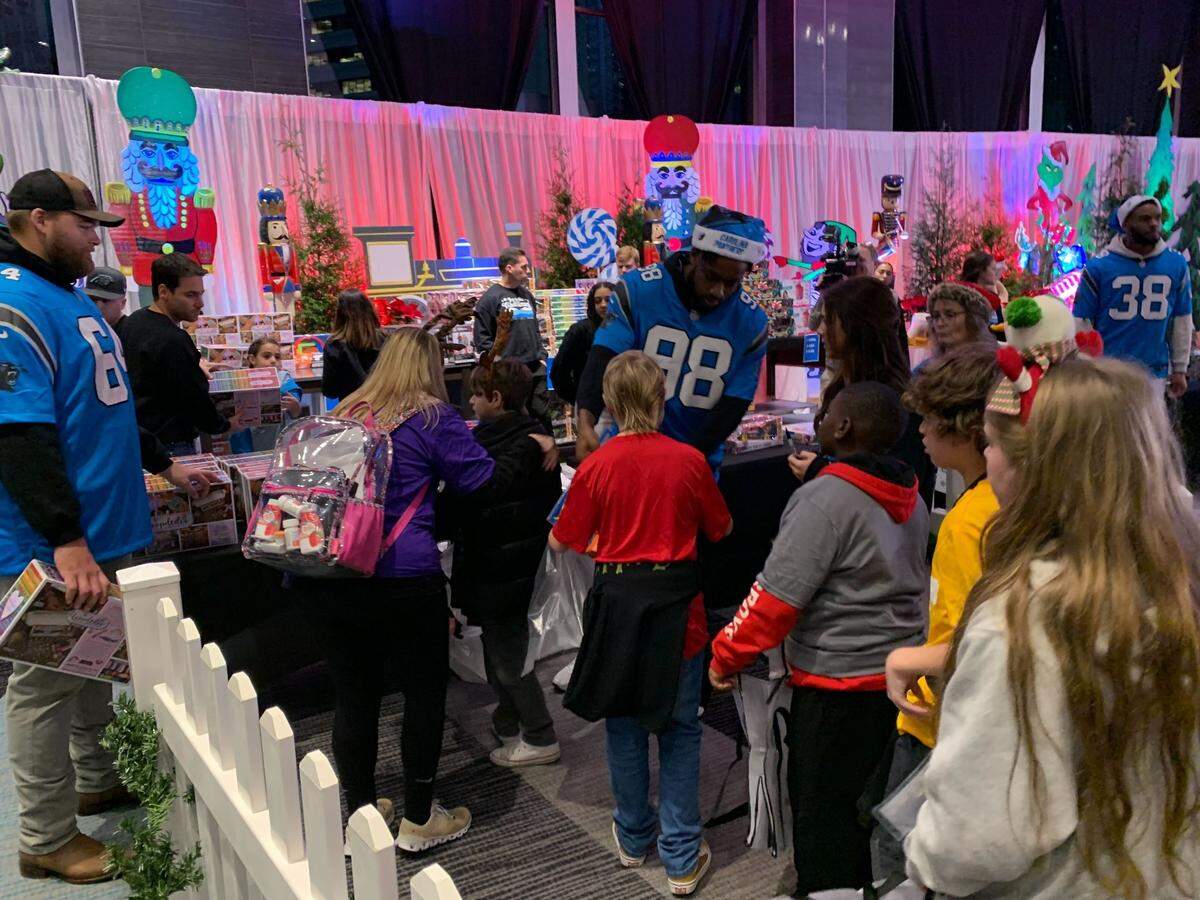 Carolina Panthers players, Cade Mays (left), D.J. Wonnum (center) and Amare Barno (right) hand out gifts to children at the sixth annual “Joy to the Carolinas” event at Bank of America Stadium on Tuesday, Dec. 17, 2024.