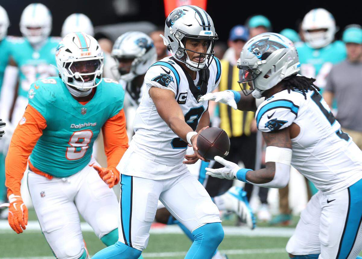 Carolina Panthers quarterback Bryce Young, center, hands the ball off to running back Rico Dowdle, right, during action against the Miami Dolphins on Sunday, October 5, 2025 at Bank of America Stadium in Charlotte, NC. The Panthers defeated the Dolphins 27-24.