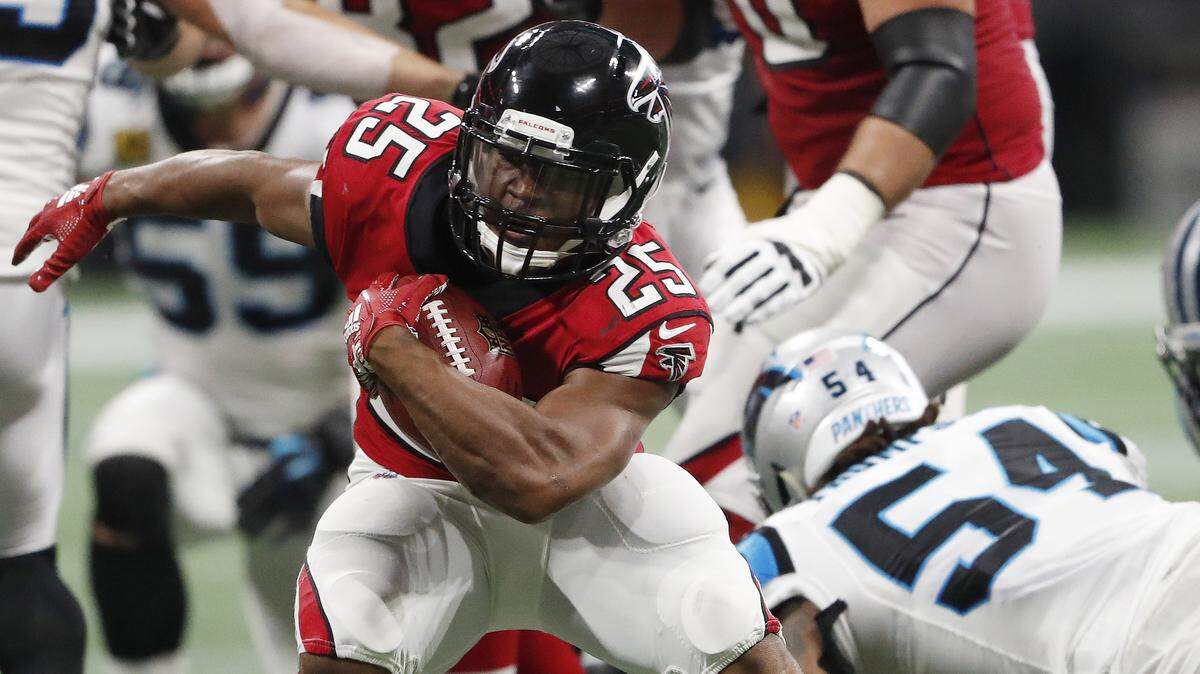Atlanta running back Ito Smith (25) runs past Carolina Panthers linebacker Shaq Thompson (54) during the second half on Sunday in Atlanta, gaining some of the Falcons’ 170 rushing yards.