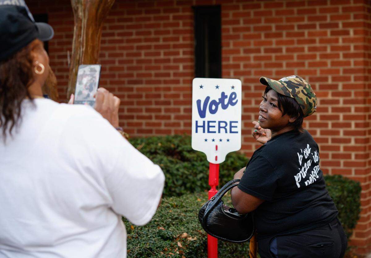 After voting, Glinda Blackwell poses for a photo next to the “Vote Here” sign at Ebenezer Baptist Church on election day in Charlotte, NC on Tuesday, November 5, 2024.