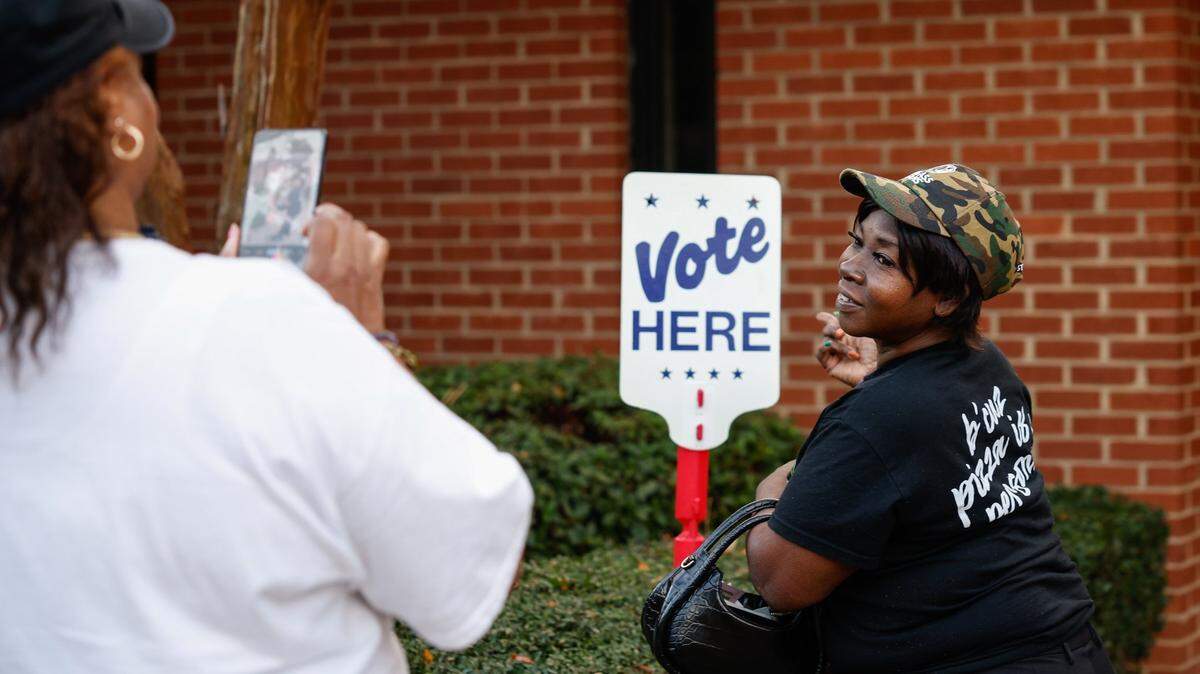 After voting, Glinda Blackwell poses for a photo next to the “Vote Here” sign at Ebenezer Baptist Church on election day in Charlotte, NC on Tuesday, November 5, 2024.