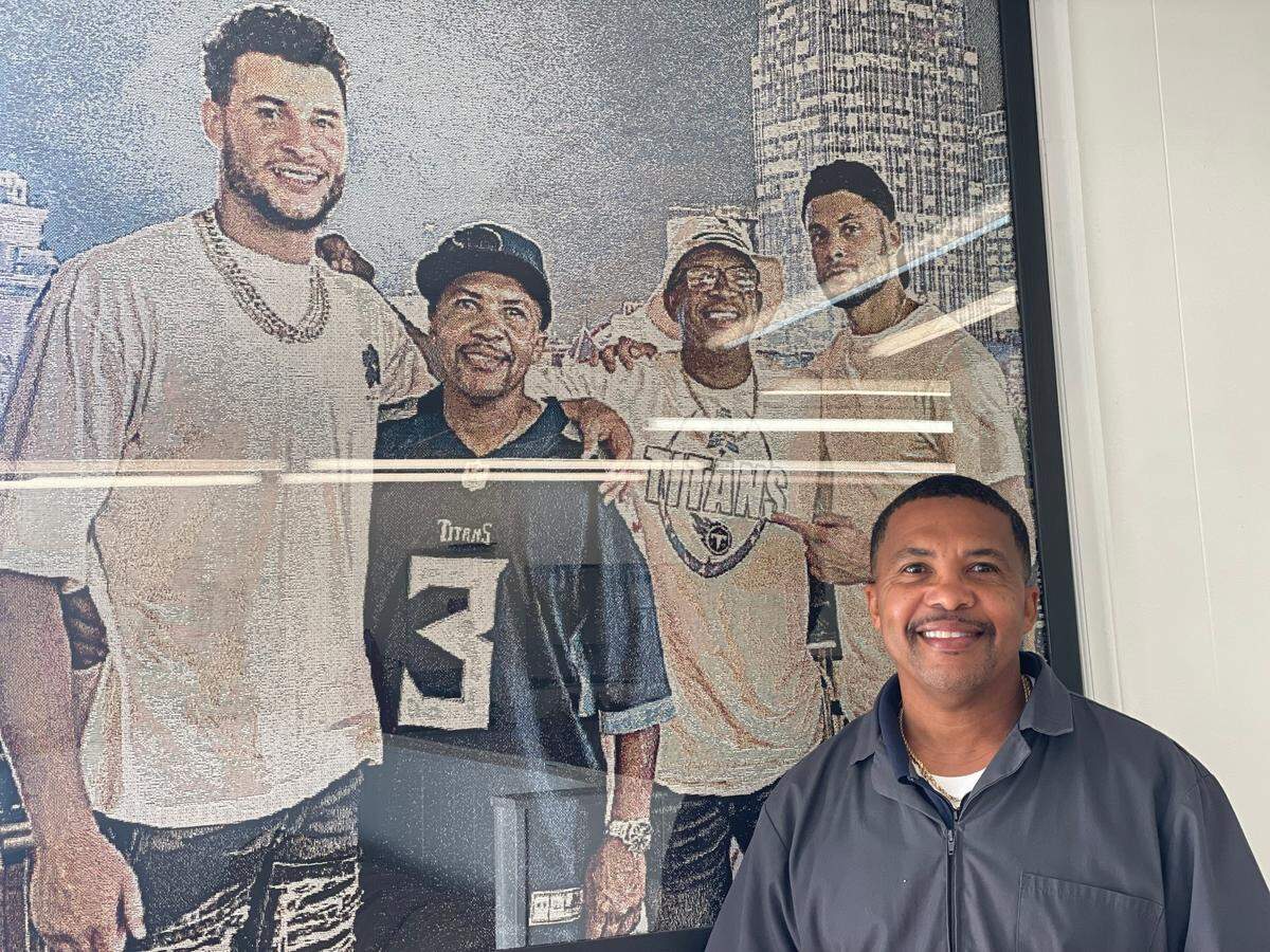 Elijah Farley stands in front of a picture hanging in his barber shop in Newton, N.C. It’s one of the last photos he has of his brother, Robert, who he ran the business with. It was taken after one of Caleb Farley’s games as a Tennessee Titan. Pictured from left to right in the photo: Caleb Farley, Elijah Farley, Robert Farley and Joshua Farley (Caleb’s older brother).