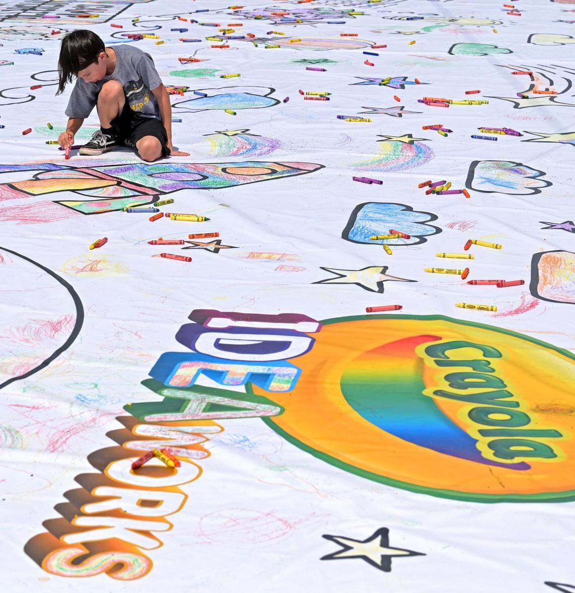 Adrian Grady, 9, colors a piece of the World’s Largest Coloring Page at Camp North End on Tuesday, July 12, 2022. The Coloring Page is part of Crayola’s IDEAworks, the ultimate creativity exhibition. The coloring page is over 1,000 square feet and is an attempt to break Crayola’s previous record of 770 square feet that was colored in the Netherlands in 2021. The coloring page features iconic Charlotte landmarks.