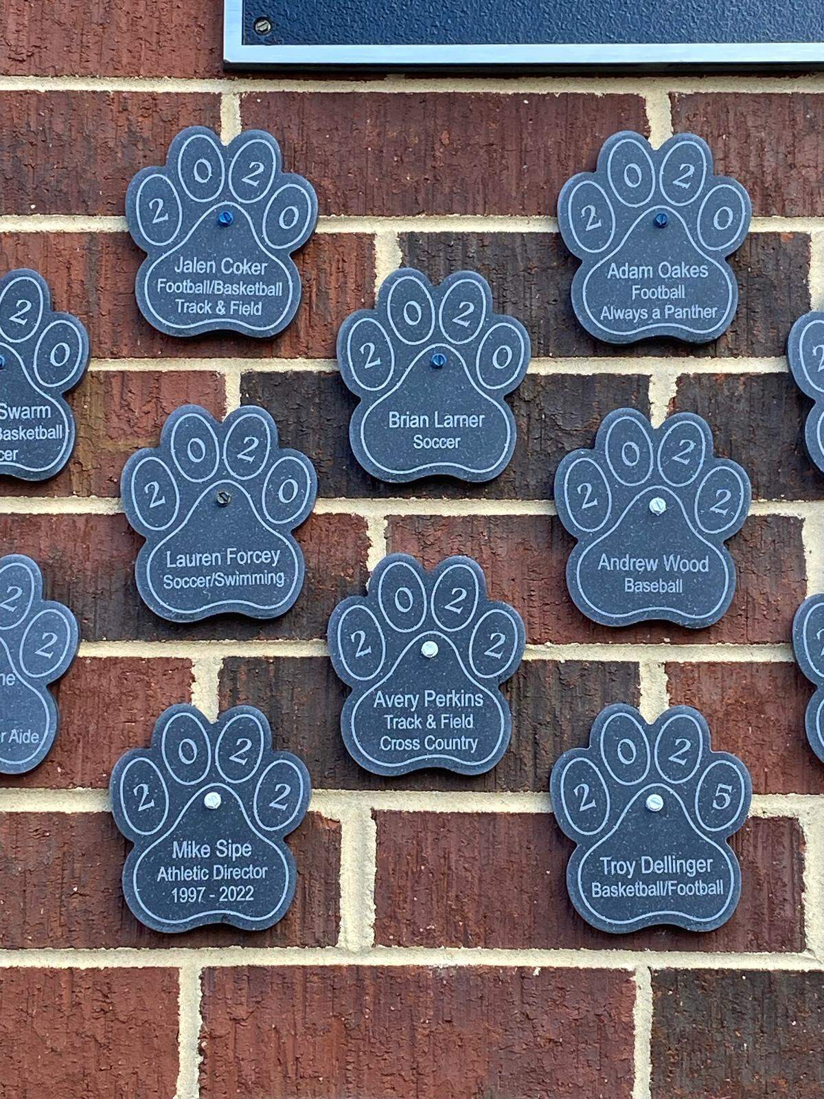 Jalen Coker, left, and Adam Oakes, right, are recognized on a “legacy wall” at Potomac Falls High School in Virginia. 