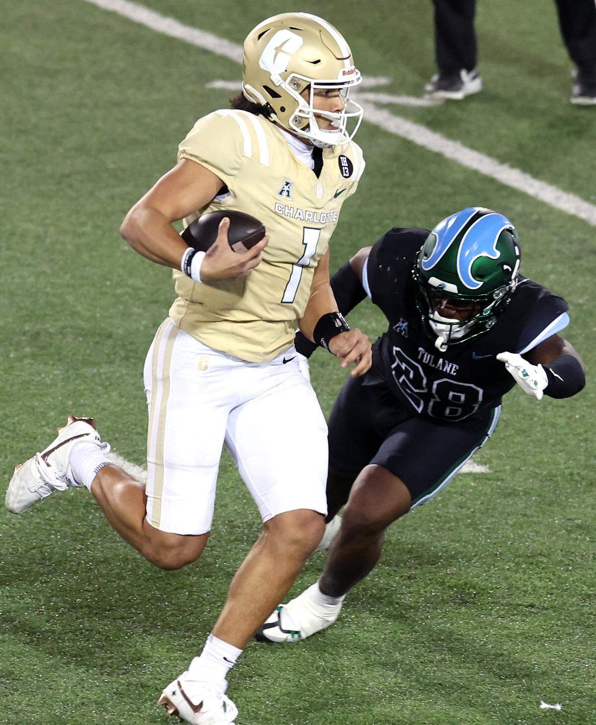 Charlotte 49ers quarterback Max Brown, left, rushes for yardage as Tulane linebacker Dickson Agu, right, looks to make the tackle on Thursday, October 31, 2024 at Jerry Richardson Stadium in Charlotte, NC.