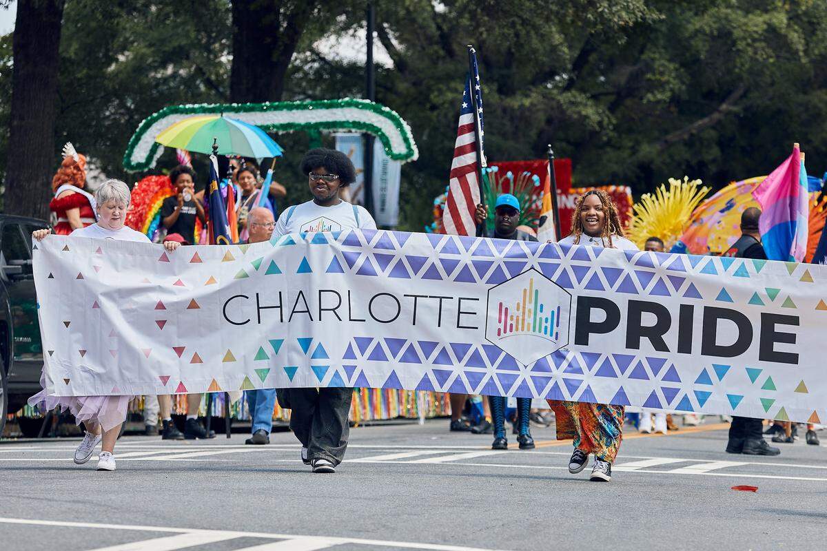 The opening banner of the Charlotte Pride Parade walks down North Tyron Street during the 25th Charlotte Pride Parade in uptown Charlotte on August 17, 2025.