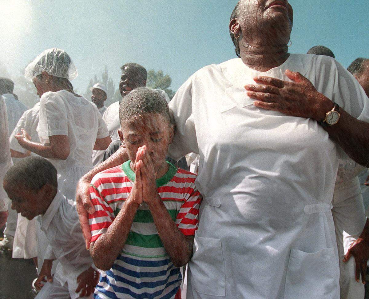 10/11/98 Trevas D. Mercer Jr. of Charlotte clasps his hands together as he is baptized with his grandmother, Saint Judy Thompson of Massachusetts at the United House of Prayer for All People on Freedom Dr. Sunday morning. Thousands were baptized during the service.