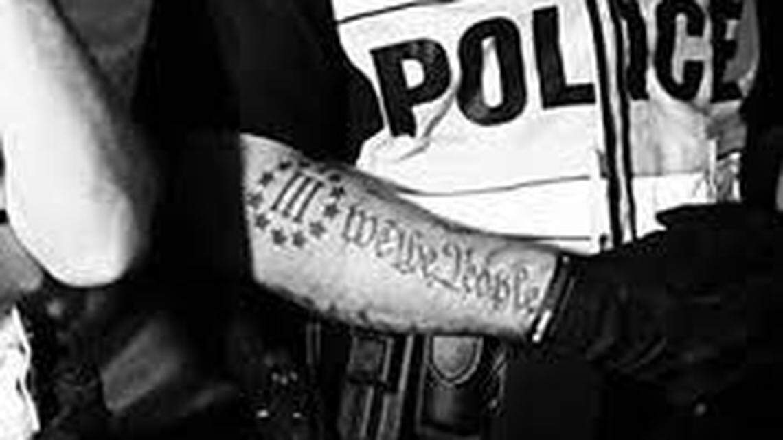 The tattoo in question has 12 stars encircling the Roman numeral three whereas the Three Percenter logo has 13.  Screenshot from Twitter.