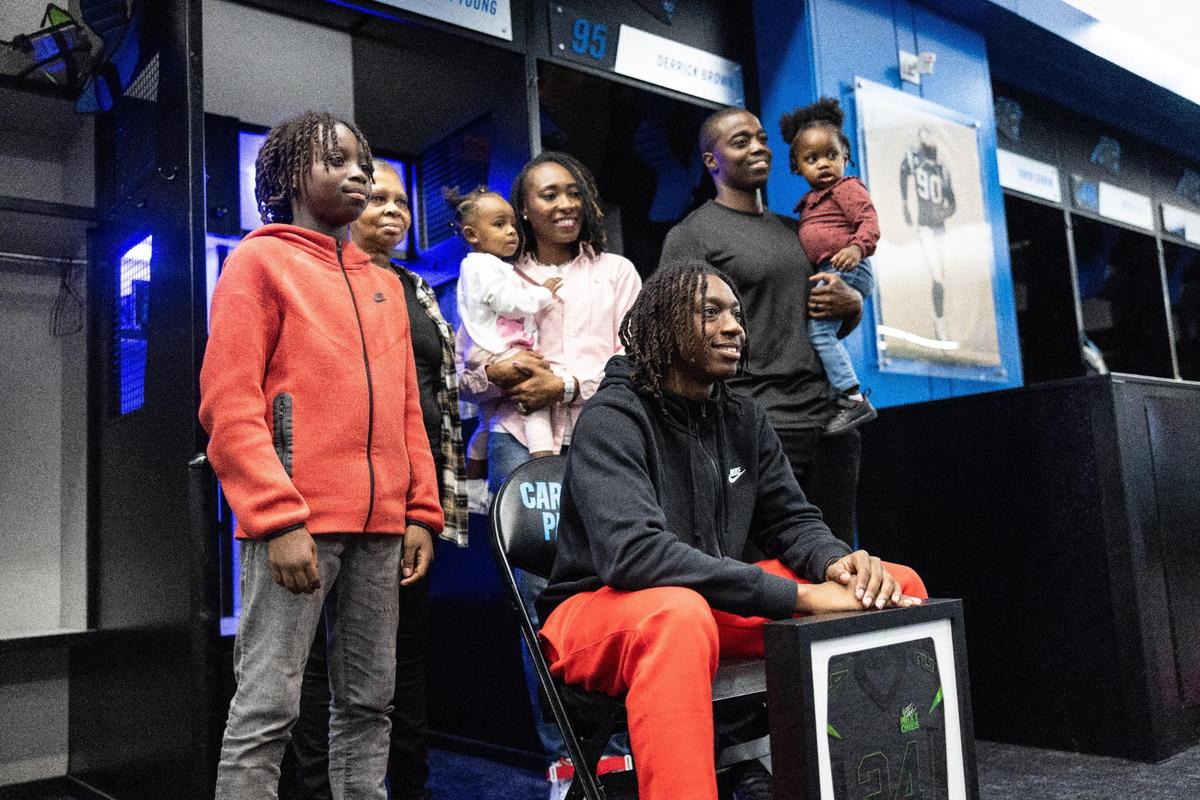 Monroe High football star Jordan Young poses with his family next to a locker with his name on it after being invited to Nike’s “The Next Ones” camp in the locker room at the Bank Of America Stadium in Charlotte, N.C., on Friday, January 26, 2024.