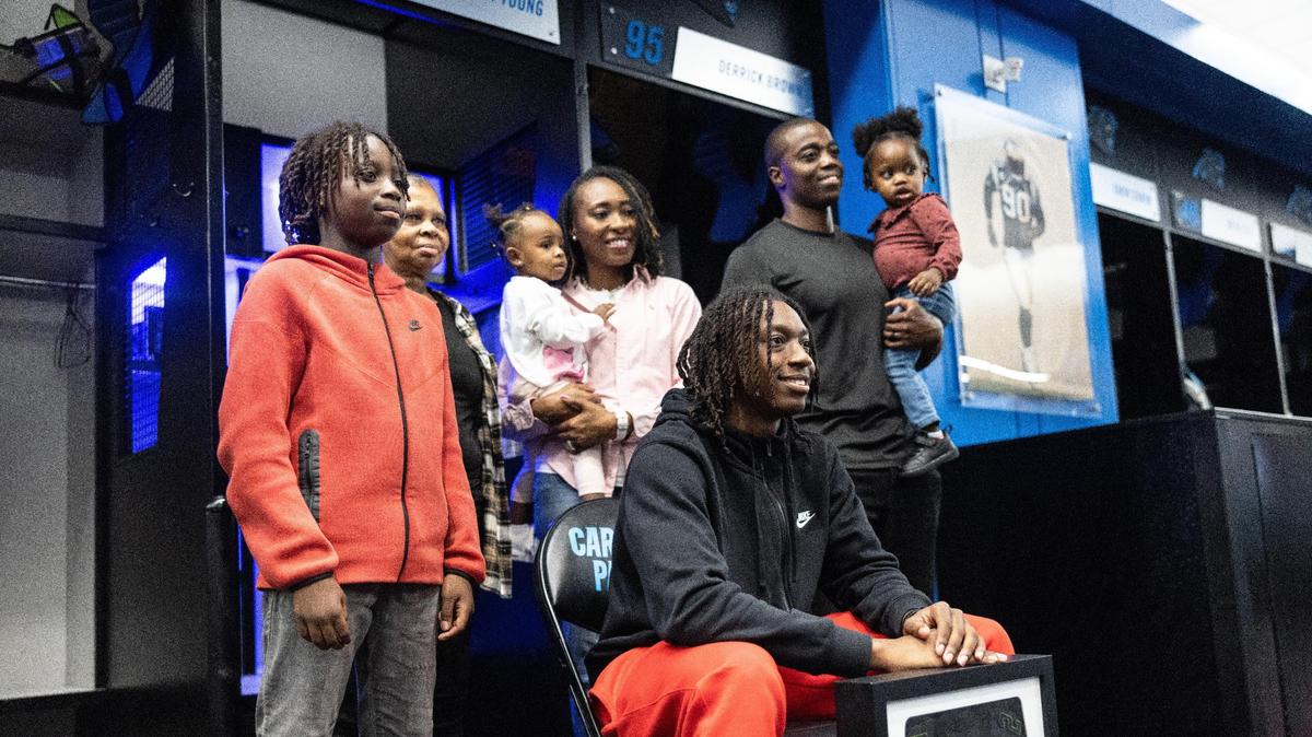 Monroe High football star Jordan Young poses with his family next to a locker with his name on it after being invited to Nike’s “The Next Ones” camp in the locker room at the Bank Of America Stadium in Charlotte, N.C., on Friday, January 26, 2024.