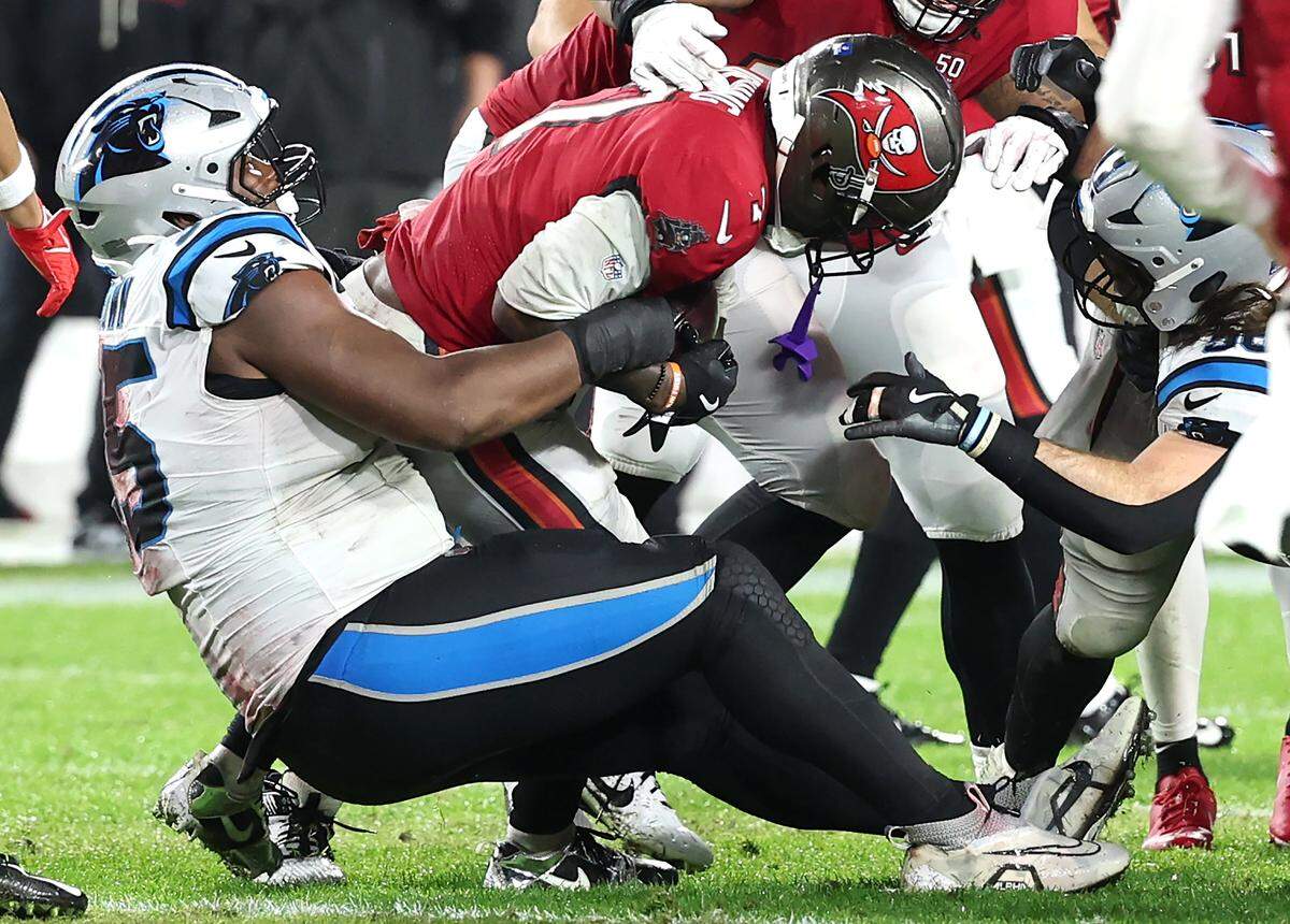 Carolina Panthers defensive tackle Derrick Brown, left, makes the tackle on Tampa Bay Buccaneers running back Bucky Irving, center, during action at Raymond James Stadium in Tampa, FL.on Saturday, January 3, 2026. The Buccaneers defeated the Panthers 16-14.