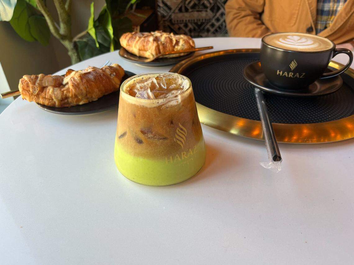 Coffee drinks, including an iced Pistachio Latte with oat milk in the foreground, and almond croissants at Haraz Coffee House in Plaza Midwood Charlotte.