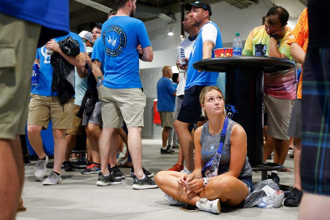 Hannah Bernard, of Matthews, sits under a table as fans are told to shelter in place during a thunderstorm which delayed the game between between Charlotte FC and Columbus Crew at Bank of America Stadium in Charlotte, N.C., Saturday, July 30, 2022.