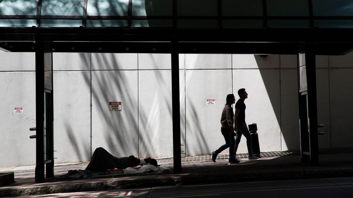 A homeless individual rests under a bus stop in Uptown Charlotte on Tuesday, June 27, 2023.