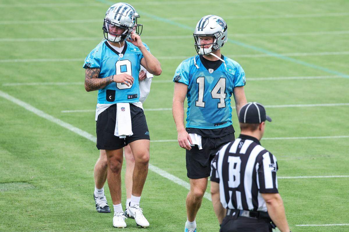 Panthers quarterbacks Matt Corral, left, and Sam Darnold, center, walk on to the practice field during day two of mini camp on Wednesday, June 15, 2022 in Charlotte, NC.