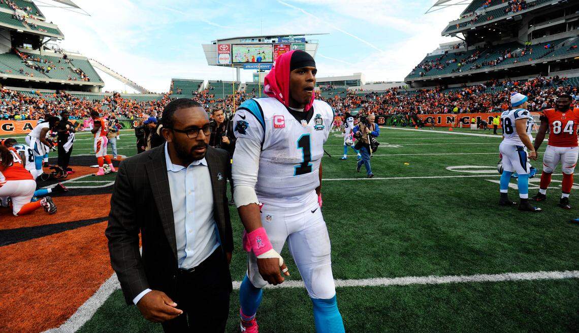 Cam Newton walks off the field with then-assistant director of communications Steven Drummond after playing Cincinnati to a tie in overtime in October 2014.
