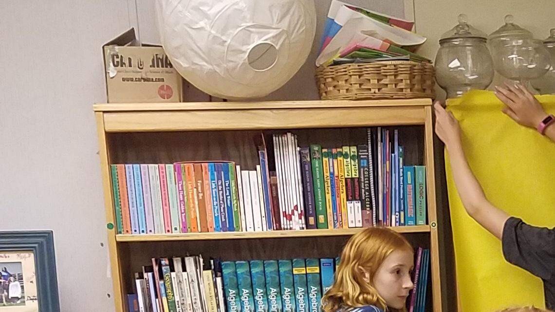 Students at Park Road Montessori School in Charlotte help teacher Sandy Wade cover bookshelves in preparation for year-end testing.