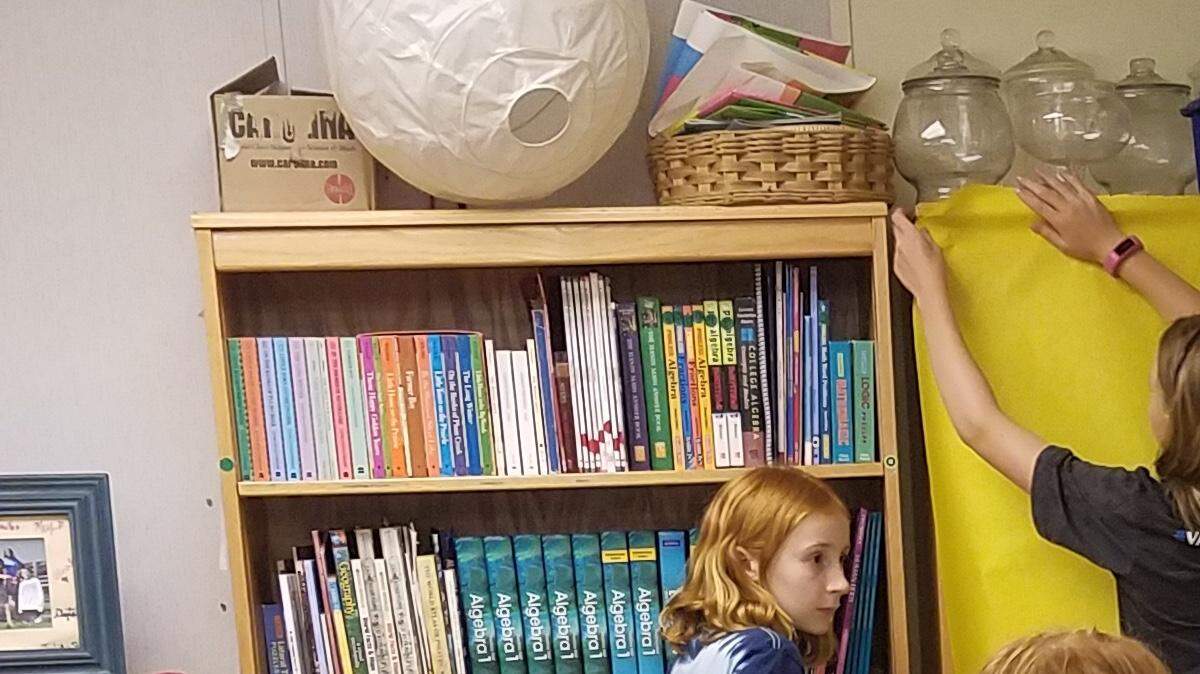 Students at Park Road Montessori School in Charlotte help teacher Sandy Wade cover bookshelves in preparation for year-end testing.