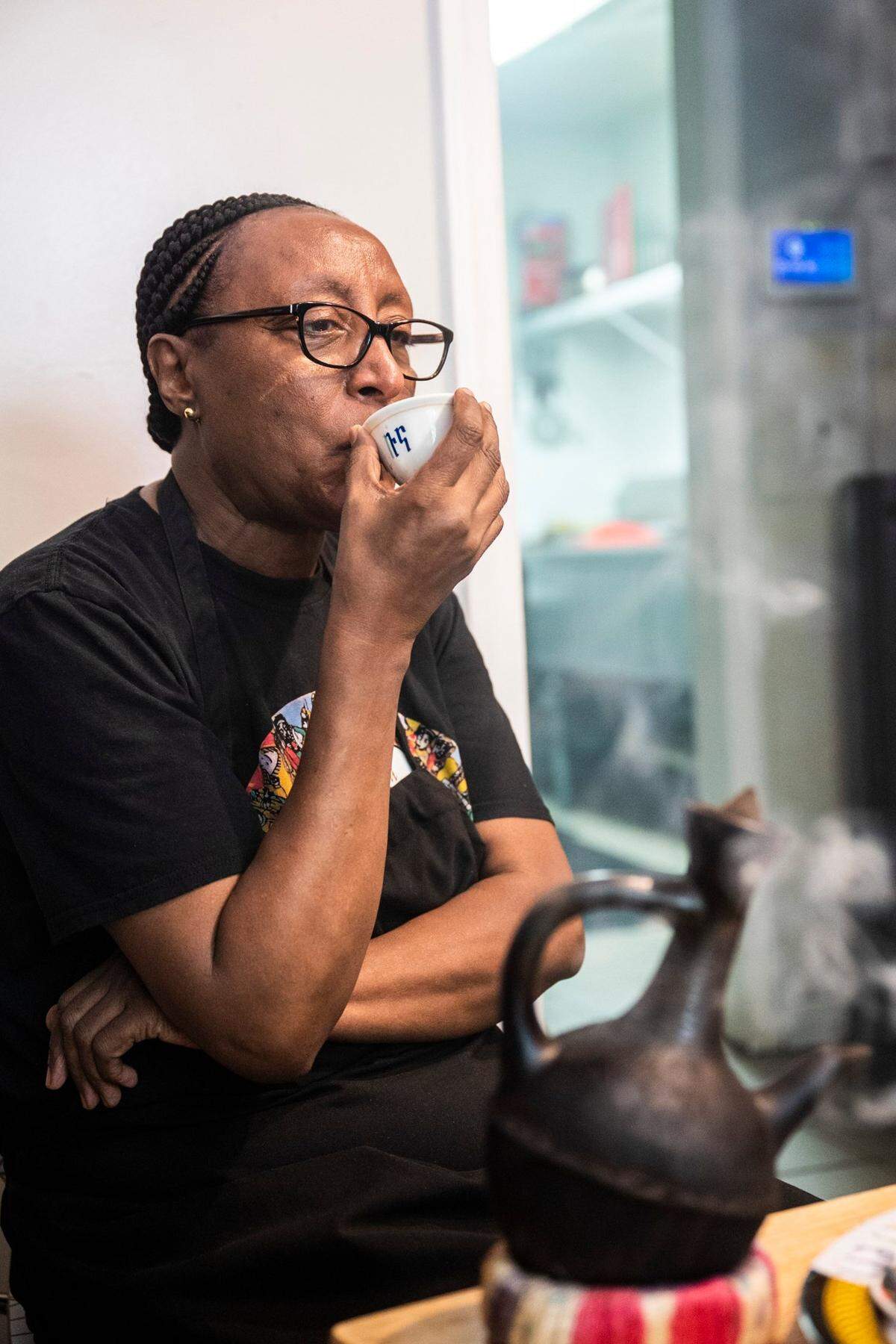 Shito Negussie sips coffee before she opens Abugida, a restaurant she owns with her daughter, Yodite Tesafye, in Charlotte.