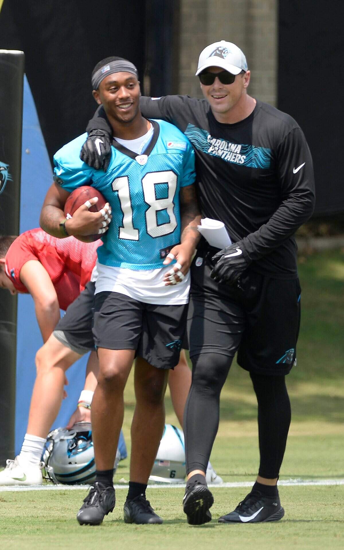 Carolina Panthers assistant special teams coordinator Heath Farwell jokes with wide receiver Damiere Byrd (18) during practice at the team's practice fields on Wednesday, August 15, 2018.