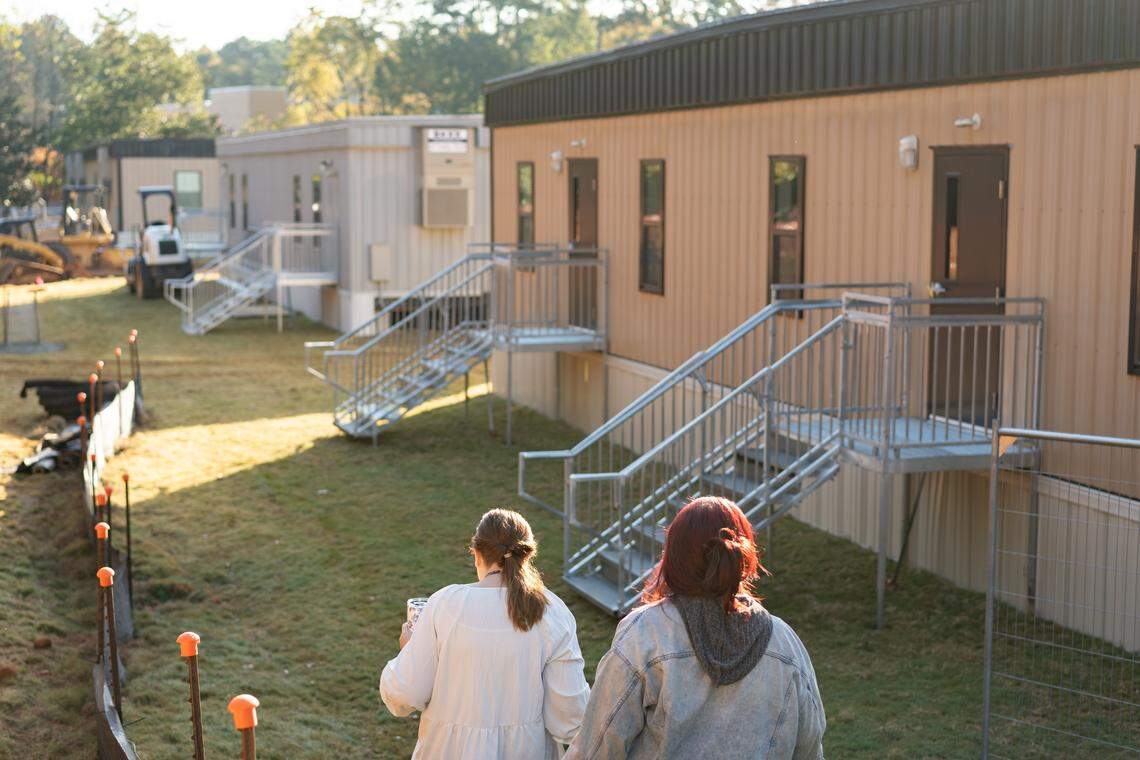 Charlotte Prep staff members pass in front of temporary modular buildings at the campus. Classes for kindergarten through fourth grade have been held in the buildings since October 2023.