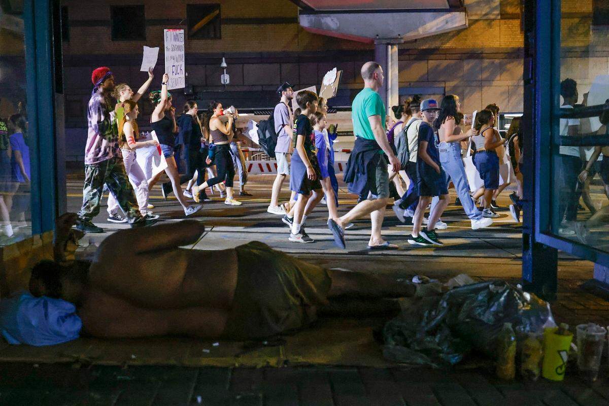 Abortion rights activists march along East Trade Street near a homeless person in Charlotte, June 26, 2022. The demonstration was in response to last week’s decision from the U.S. Supreme Court to overturn Roe v. Wade.