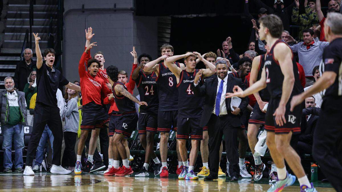 Davidson's bench reacts to a three-pointer hit by Hunter Adam, far right, with seconds left in the game against UNC Charlotte at Dale F. Halton Arena in Charlotte, NC on Tuesday, November 11, 2025. Davidson won the Battle for the Hornet's Nest by defeating UNC Charlotte, 60-55.