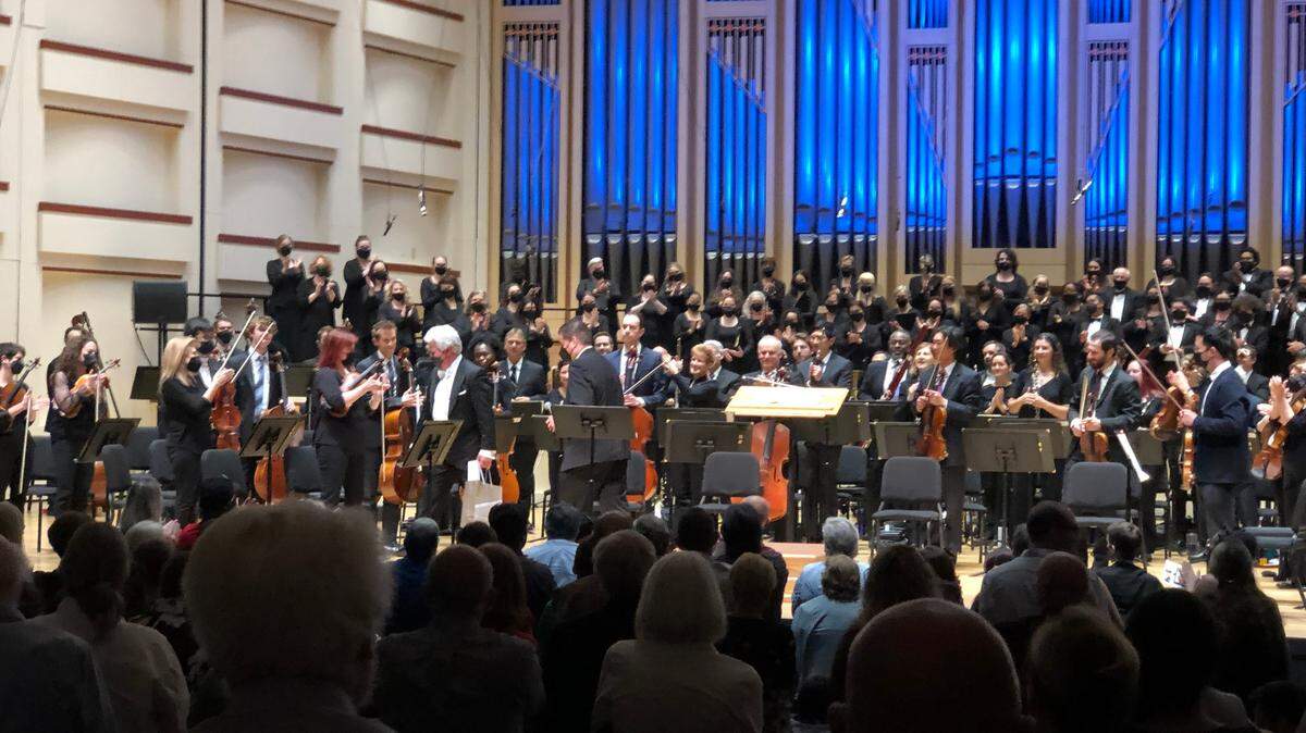 Charlotte Orchestra music conductor Christopher Warren-Green, center left, holding a small bag of gifts from the musicians, leaves the stage for the final time as the symphony’s maestro Sunday, May 22. 2022.