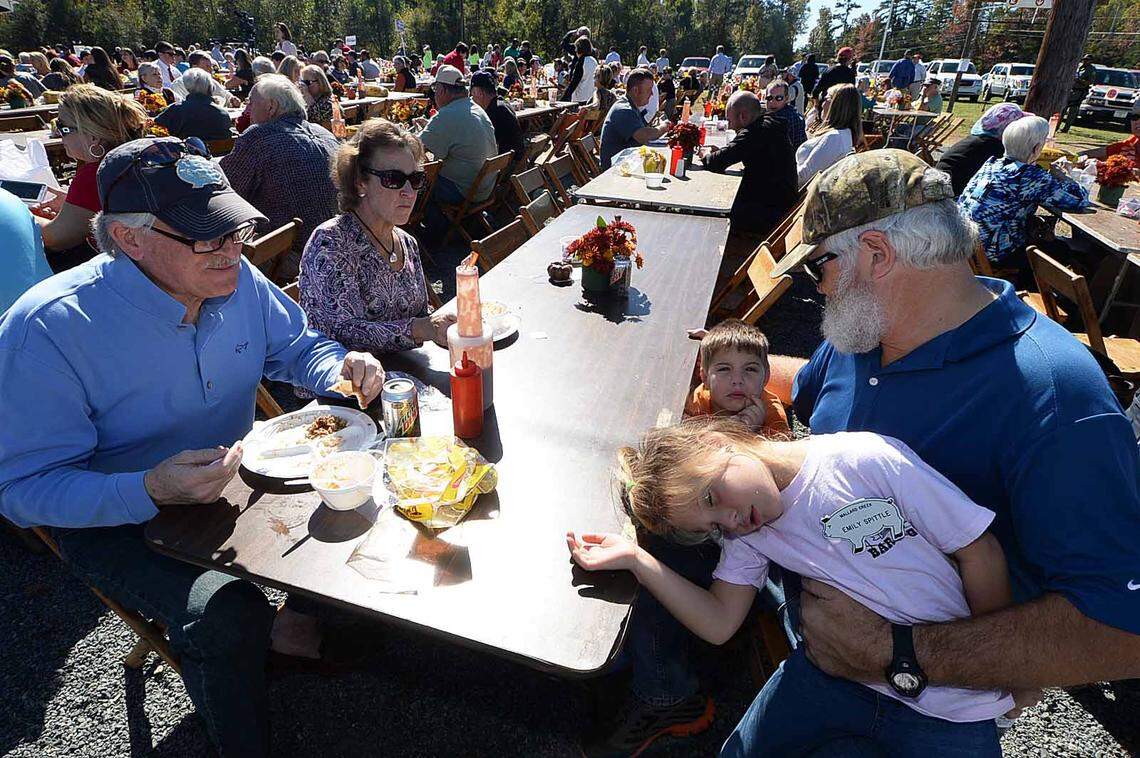 Tony Spittle sits at the picnic tables finishing a meal with his grandkids Emily, 5, front, and Trent, 3, at the annual Mallard Creek BBQ event at Mallard Creek Presbyterian Church.