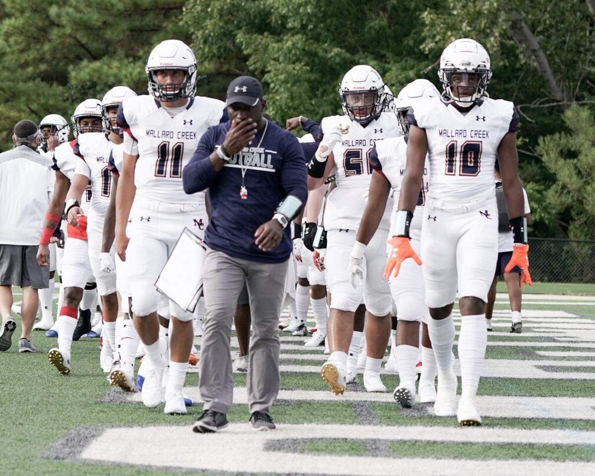 Mallard Creek walks out on the field to take on nationally ranked Dutch Fork (SC) behind assistant coach Donald Littlejohn
