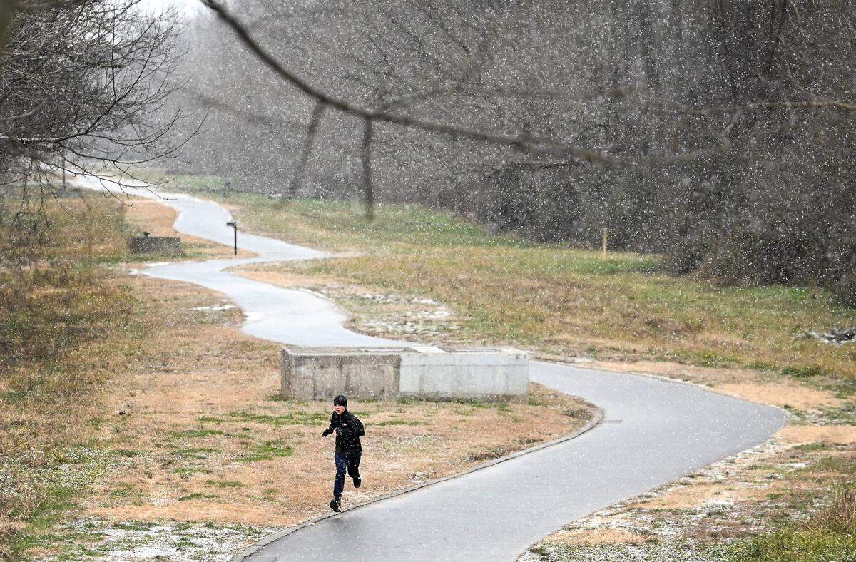 A runner runs in along the McAlpine Creek Greenway as the snow falls near Old Bell Road in Charlotte, NC on Friday, January 10, 2025.