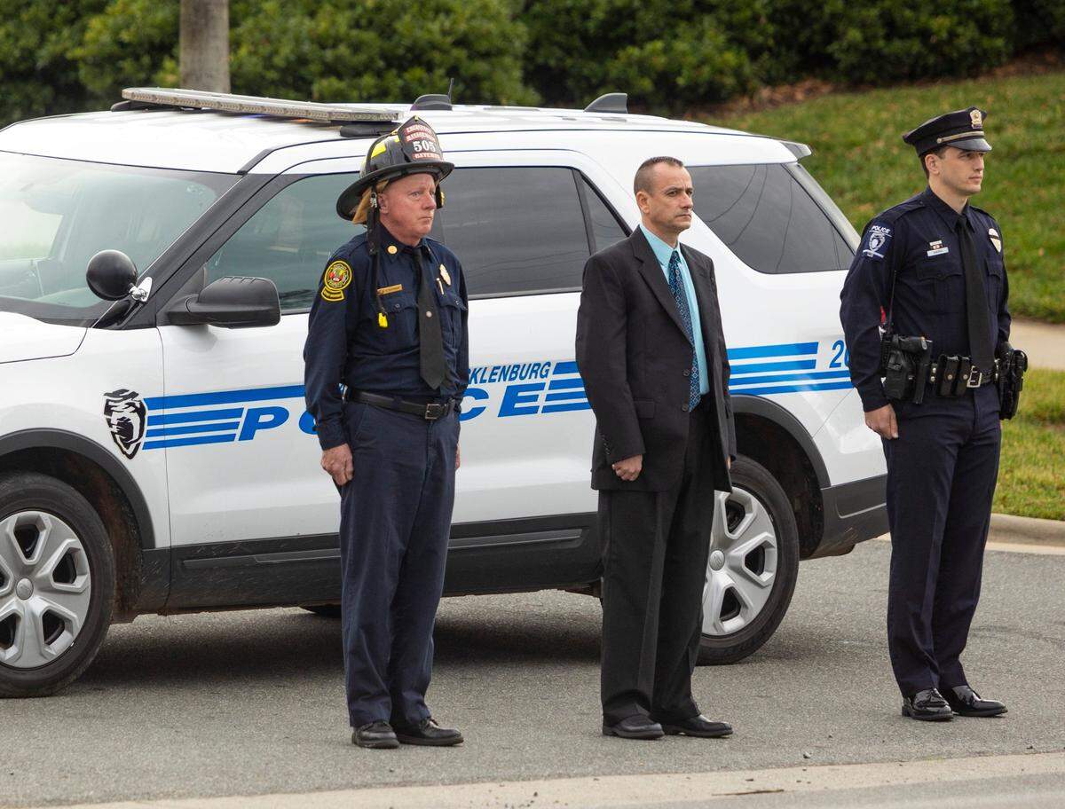 CMPD and Charlotte Fire Department stand at attention as the procession outside of the Alexander funeral home proceeds in Charlotte on Wednesday, December 29, 2021. The procession was for CMPD officer Mia Goodwin who was killed after a wreck involving two semi-trucks while she was directing traffic on duty.