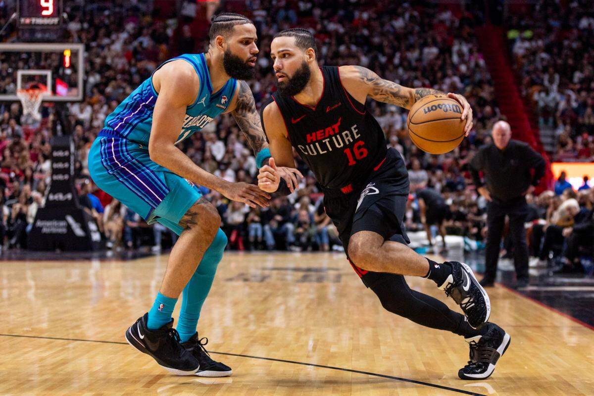 Miami Heat forward Caleb Martin (16) drives on Charlotte Hornets forward Cody Martin (11) during the second half of an NBA game at Kaseya Center in Miami, Florida, on Sunday, January 14, 2024.