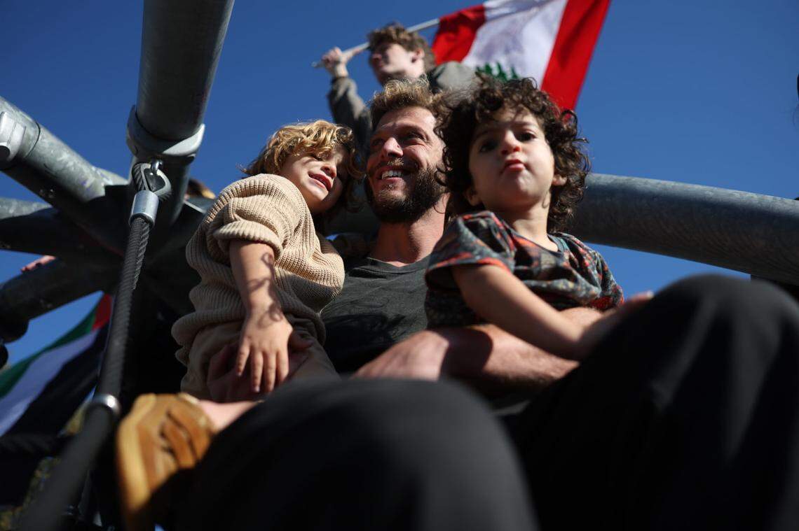 A man and two children sit atop a metal structure in First Ward Park as the ‘No Kings’ protest marches through uptown Charlotte on Saturday, Oct. 18.