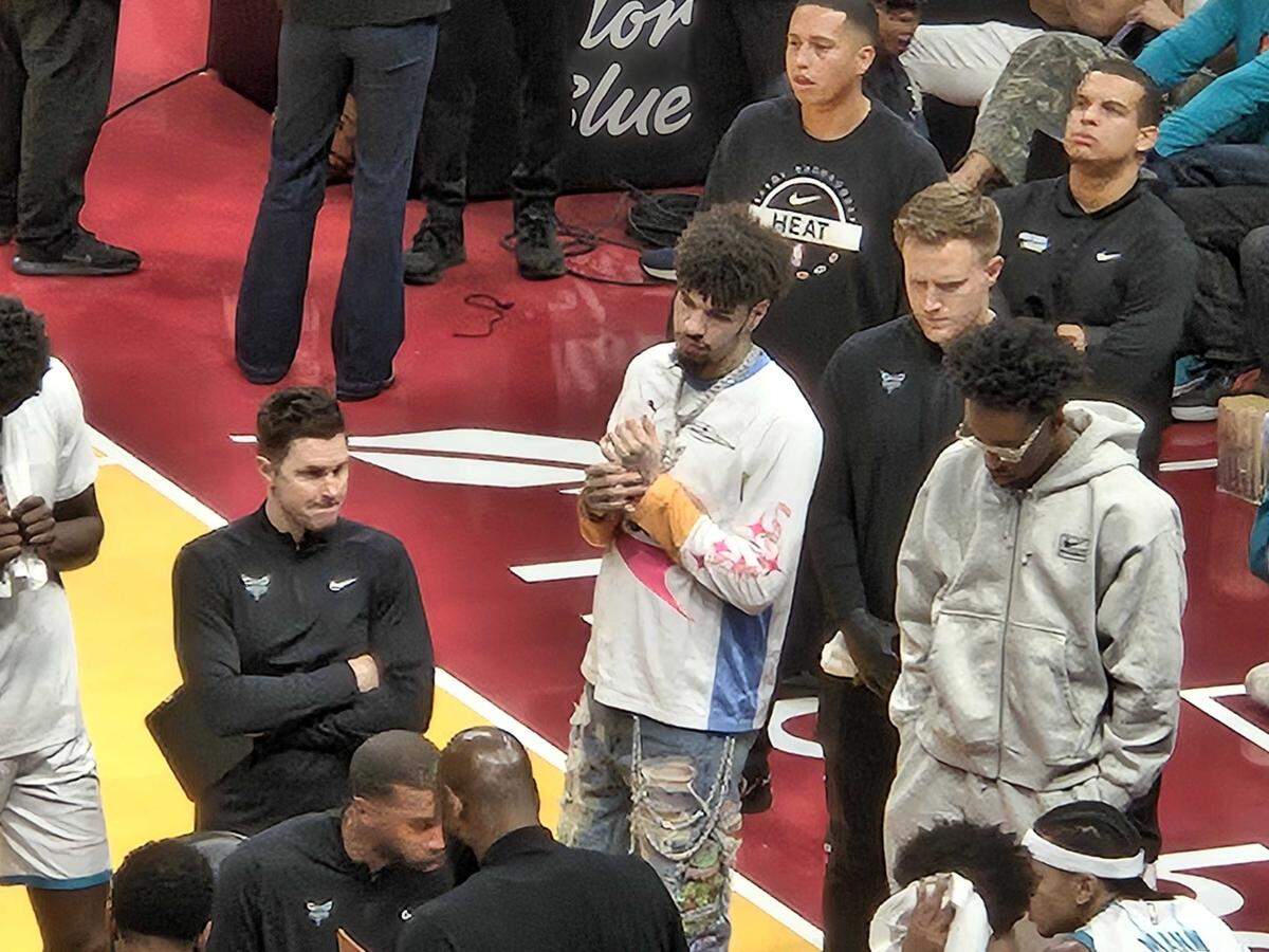 Charlotte Hornets star LaMelo Ball (center, white shirt) was in street clothes for Friday night’s game at the Miami Heat.