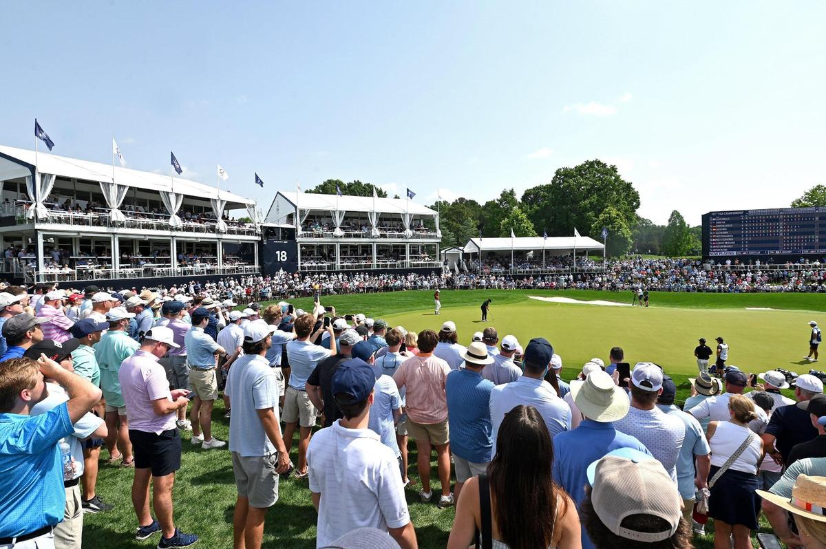 Fans wrap around the 18th green as golfers Rory McIlroy, Scottie Scheffler and Xander Schauffele putt out on the 18th green during the opening round of the 107th PGA Championship at Quail Hollow Club in Charlotte, NC on Thursday, May 15, 2025.