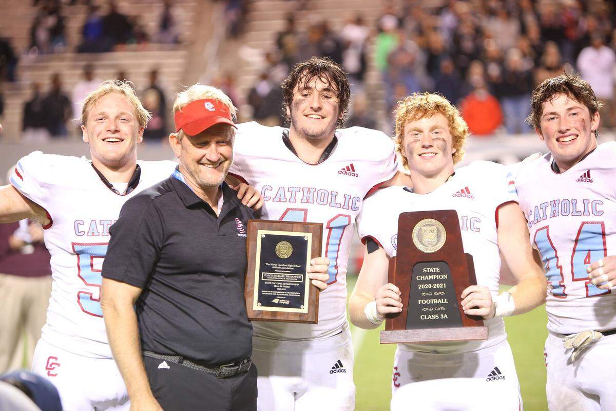 Charlotte Catholic head coach Mike Brodowicz poses with his team captains and the championship trophies following the NCHSAA 3A State Championship football game between Charlotte Catholic and Havelock in Raleigh on Friday, May 7, 2021. Charlotte Catholic won the championship game 14-7.