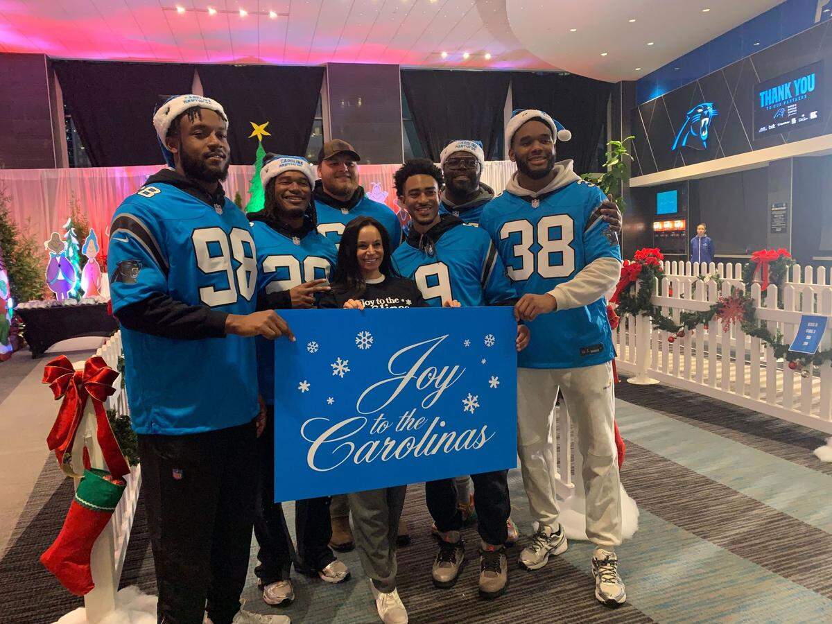 Nicole Tepper (center) poses with Carolina Panthers players (from left to right), D.J. Wonnum (98), Velus Jones Jr. (28), Cade Mays (64), Bryce Young (9), A’Shawn Robinson (94) and Amare Barno (38) at the sixth annual “Joy to the Carolinas” event at Bank of America Stadium on Tuesday, Dec. 17, 2024.