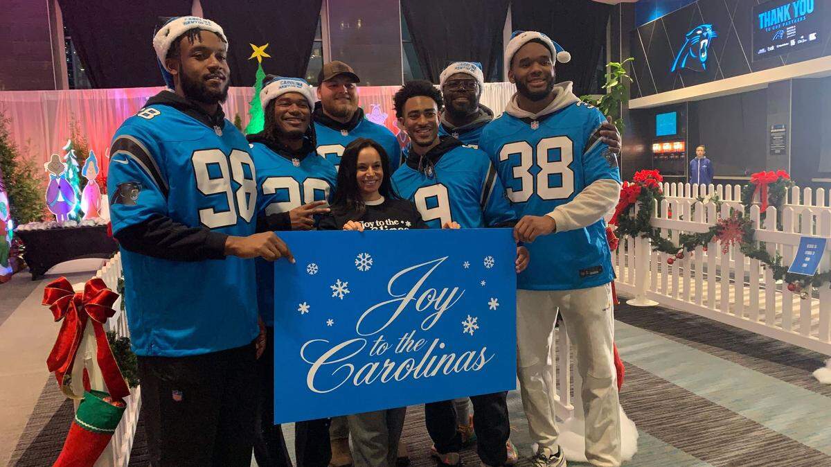 Nicole Tepper (center) poses with Carolina Panthers players (from left to right), D.J. Wonnum (98), Velus Jones Jr. (28), Cade Mays (64), Bryce Young (9), A’Shawn Robinson (94) and Amare Barno (38) at the sixth annual “Joy to the Carolinas” event at Bank of America Stadium on Tuesday, Dec. 17, 2024.
