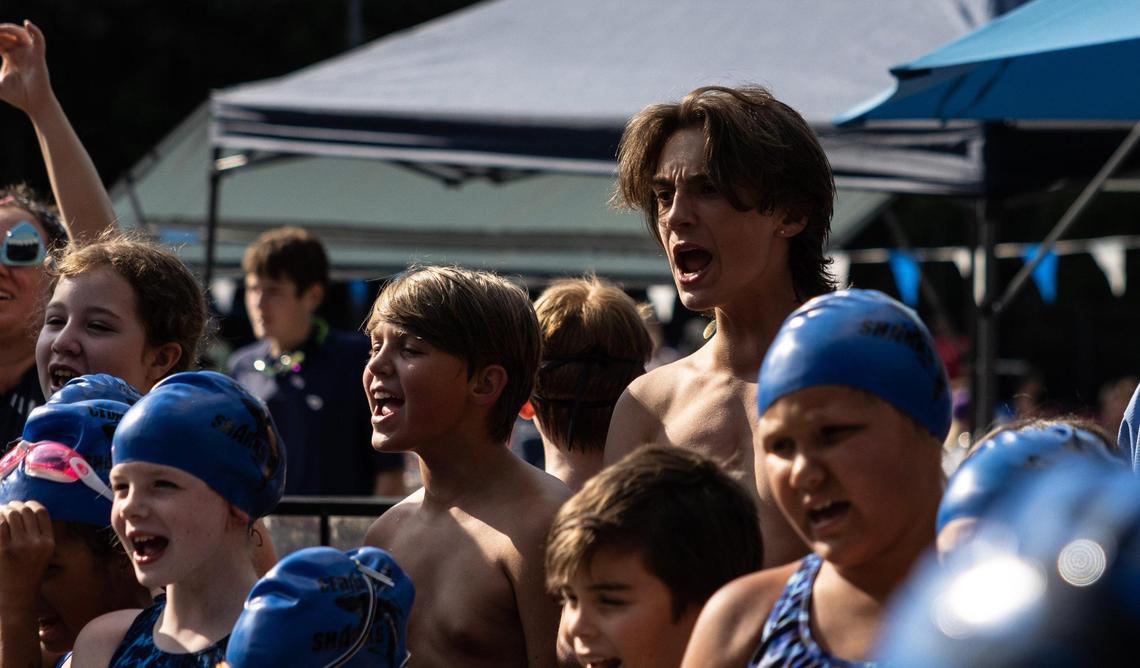 Mike Dumas, left, and his brother, TJ, yell a chant with their swim team in Huntersville. Mike’s parents say he excels in sports, and they gush about his butterfly stroke.