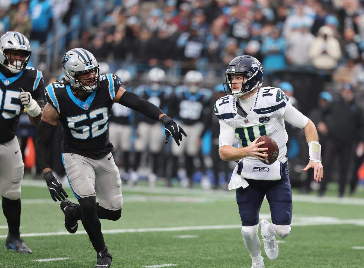 Seattle Seahawks quarterback Sam Darnold, right, carries the ball as two Carolina Panthers defenders apply pressure during Sunday’s game at Bank of America Stadium in Charlotte.
