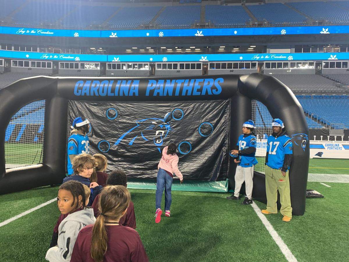 An young attendee of “Joy of the Carolinas” throws as a football as rookie safety Demani Richardson (left) and rookie wide receivers Jalen Coker (middle) and Xavier Legette (right) watch on Tuesday, Dec. 18, 2024 (12/18/2024).
