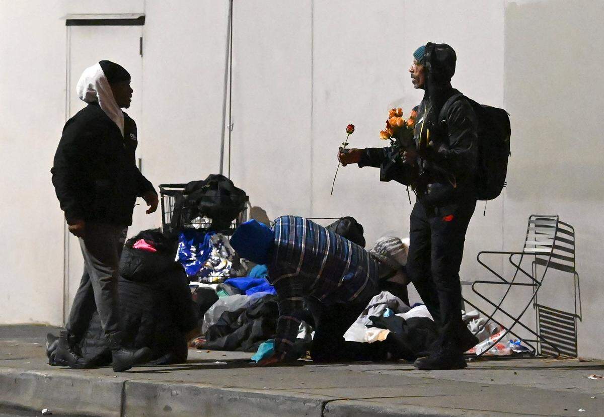 Chauncey Williams, right, offers a rose to Point-in-Time Count volunteer Jerald Collins, left, along Church St. in uptown Charlotte, NC., on Thursday, January 26, 2023.
