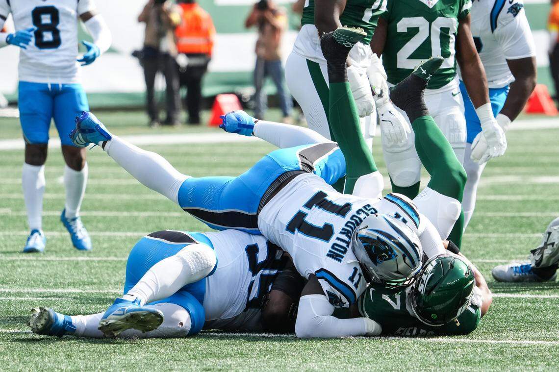 bOct 19, 2025; East Rutherford, New Jersey, USA; New York Jets quarterback Justin Fields (7) is brought down by Carolina Panthers defensive end Derrick Brown (95) and outside linebacker Nic Scourton (11) at MetLife Stadium. Mandatory Credit: Robert Deutsch-Imagn Images
