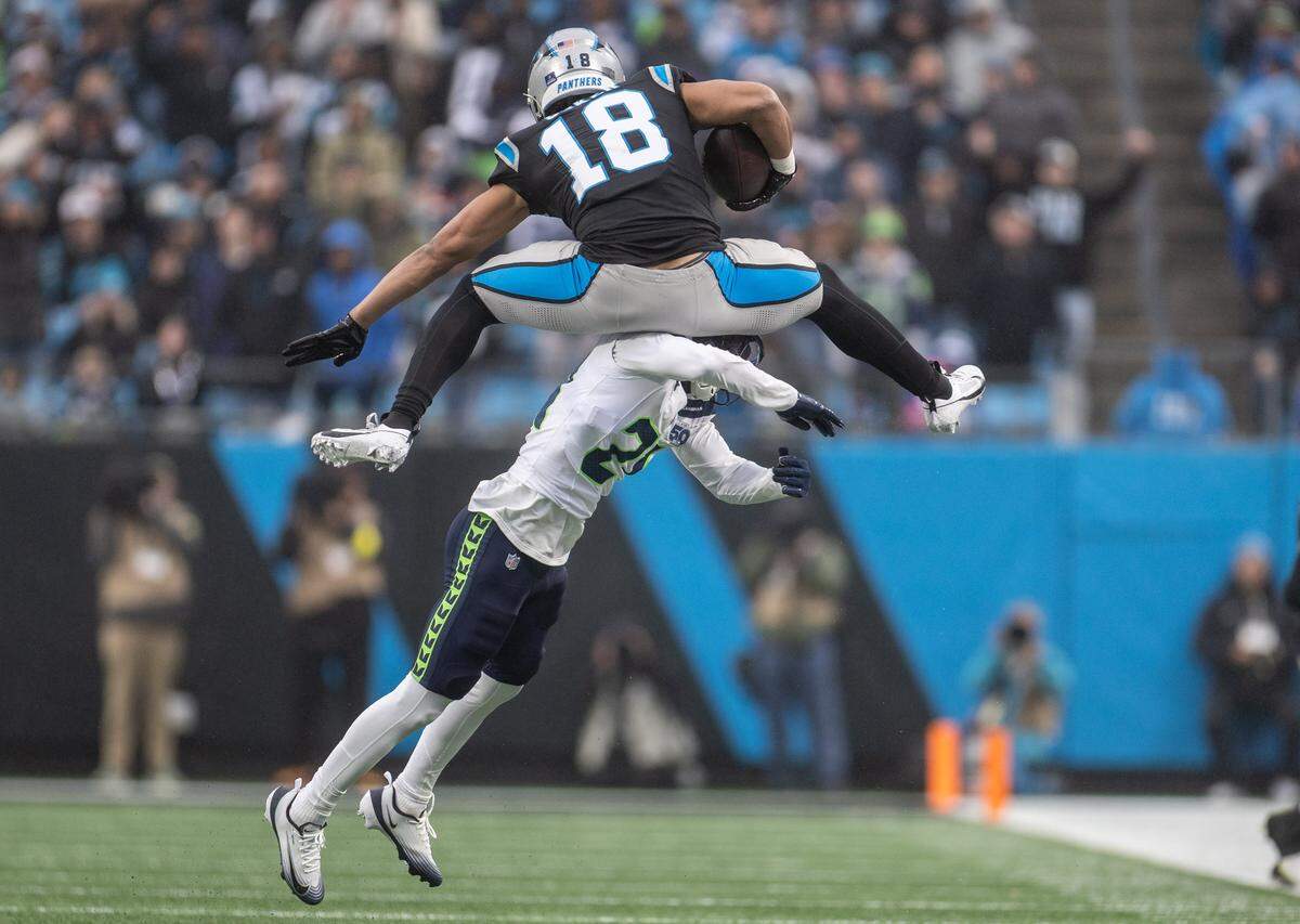 Carolina Panthers wide receiver Jalen Coker leaps over Seattle Seahawks cornerback Devon Witherspoon at the Bank of America Stadium in Charlotte, N.C., on Sunday, December 28, 2025.