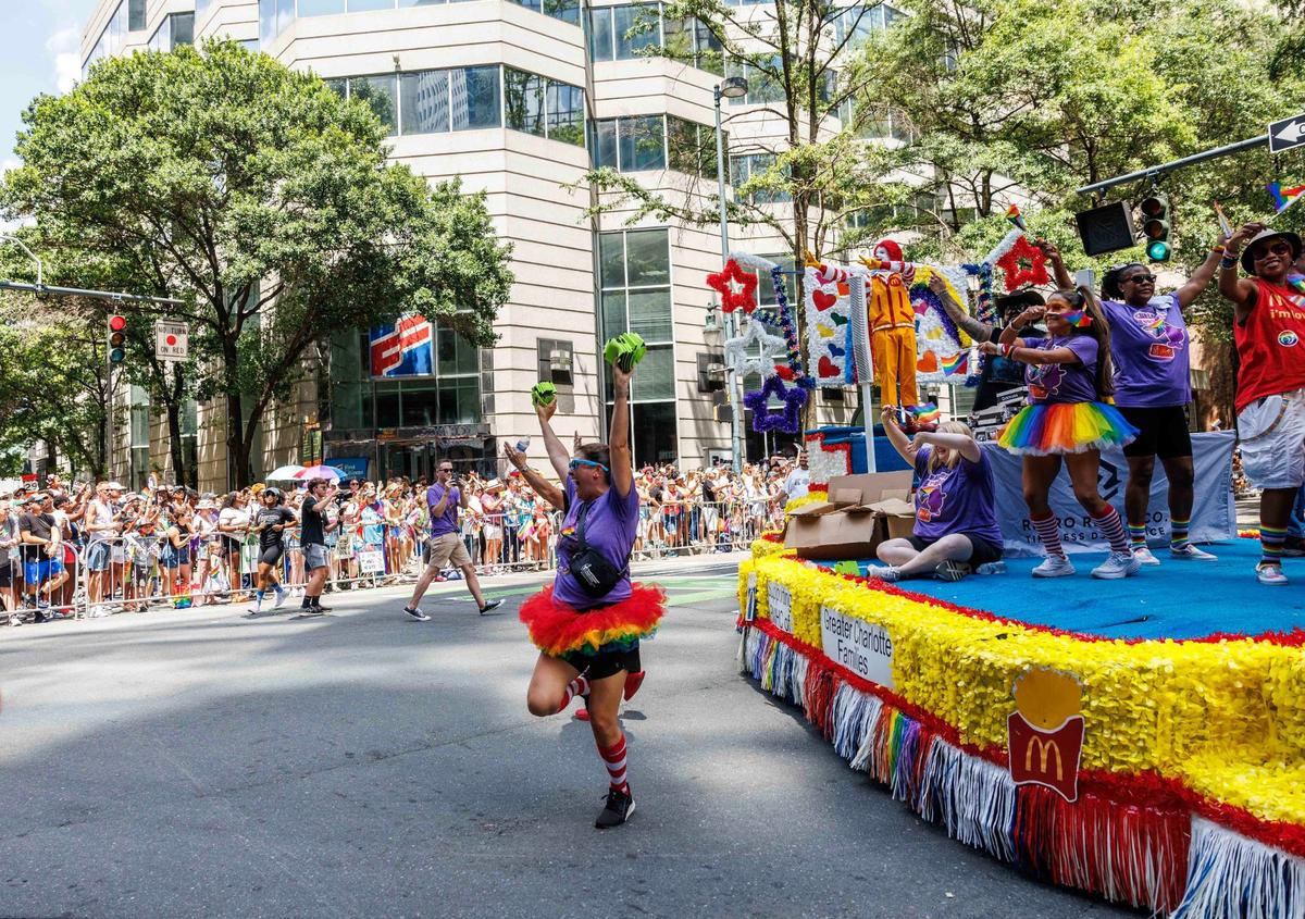 Participants representing Ronald McDonald House Charities of Greater Charlotte cheer and dance on the float, while members on the ground hand out swag items to the audience during the Charlotte Pride Festival & Parade on Sunday, Aug. 18, 2024