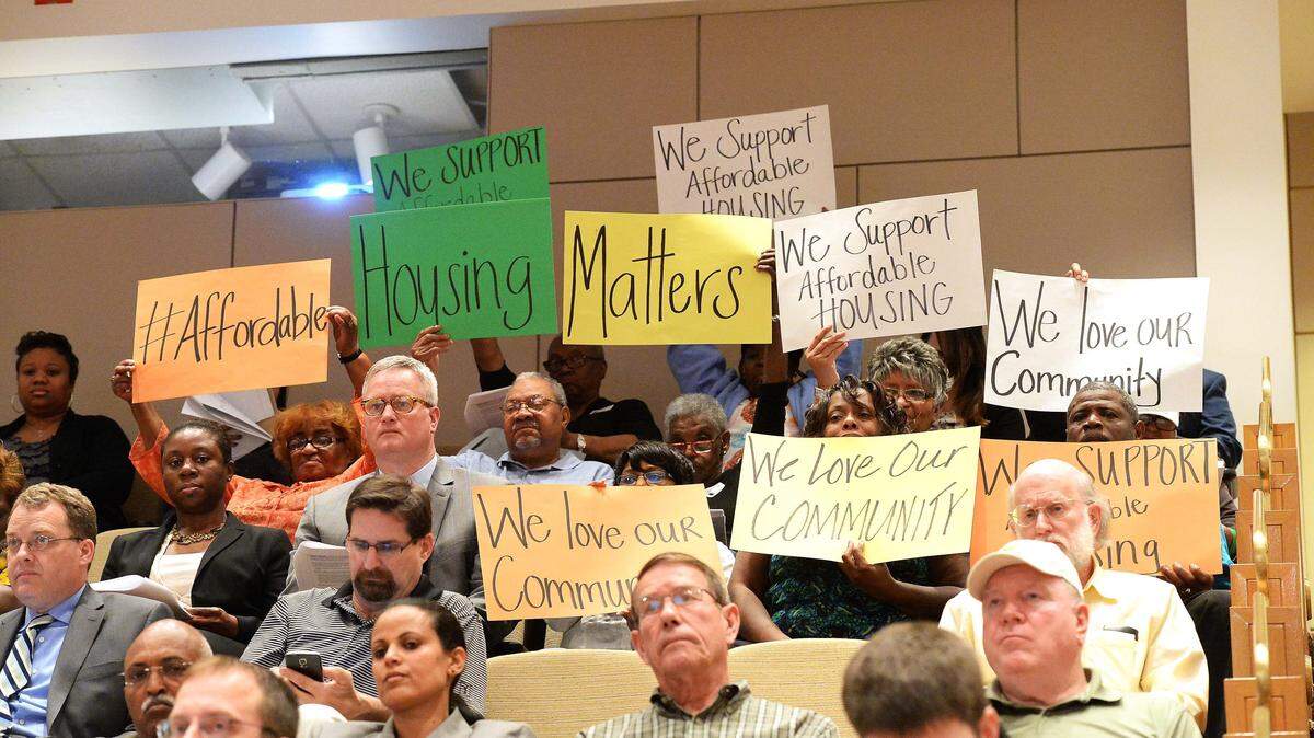 Cherry neighborhood representatives hold signs up in favor of affordable housing at Monday night's zoning meeting, March 16,2015.